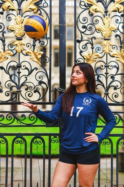 Tara with a volleyball standing outside All Souls College gates