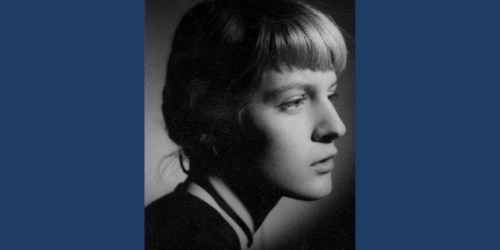 A black and white portrait photo of a young woman with tied-back blonde hair and a fringe