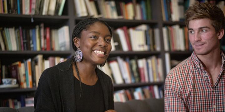 Two students enjoying a tutorial with a bookshelf in the background